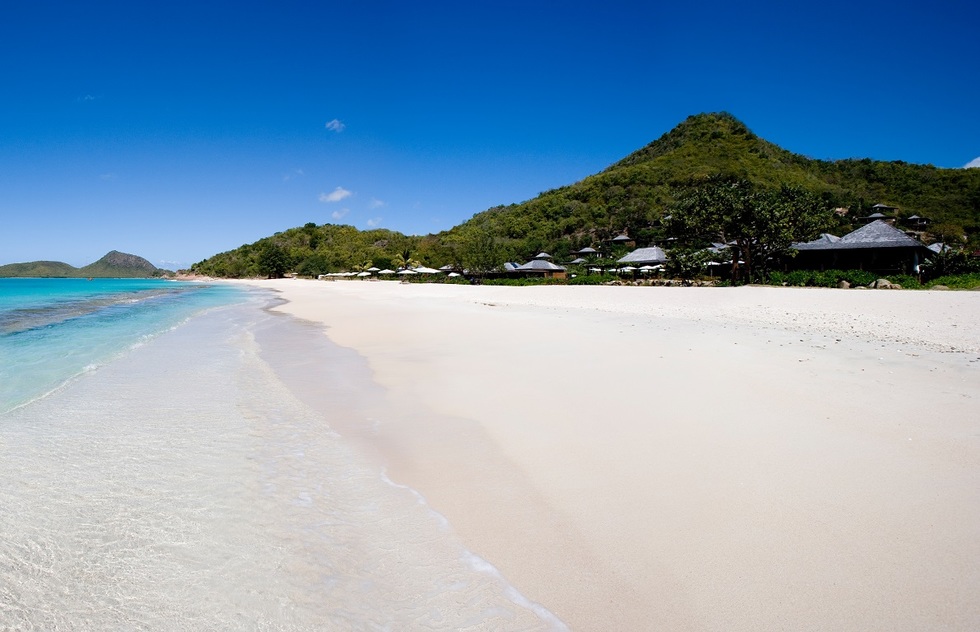 A long strip of sand stretches out between the waters of Hermitage Bay and a hillside.